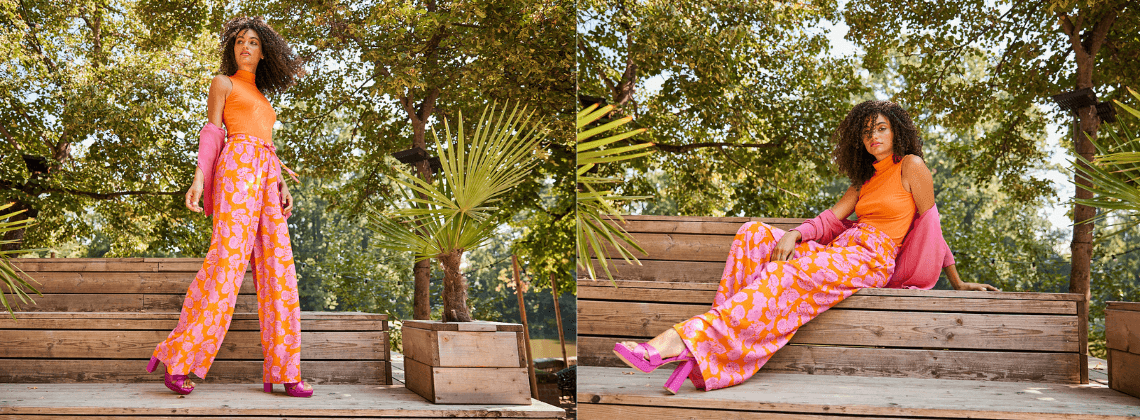 Vrouw met een oranje flared jeans met roze bloemen op een houten trapje