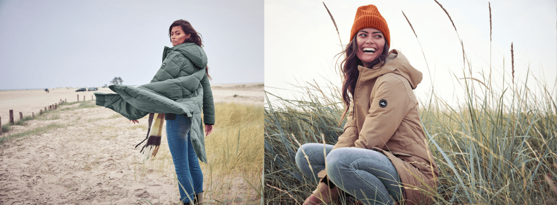 Vrouw op het strand met een winterjas aan en een sjaal om