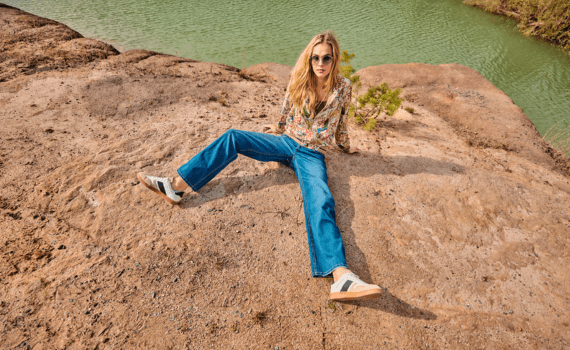 Vrouw zittend op een berg met een riviertje erachter met straight jeans aan