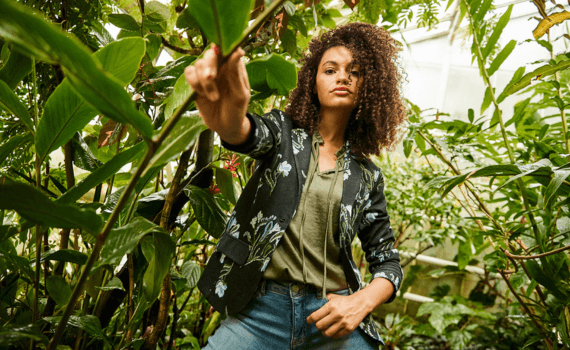 Vrouw in een zwart bloemetjes blazer tussen de planten